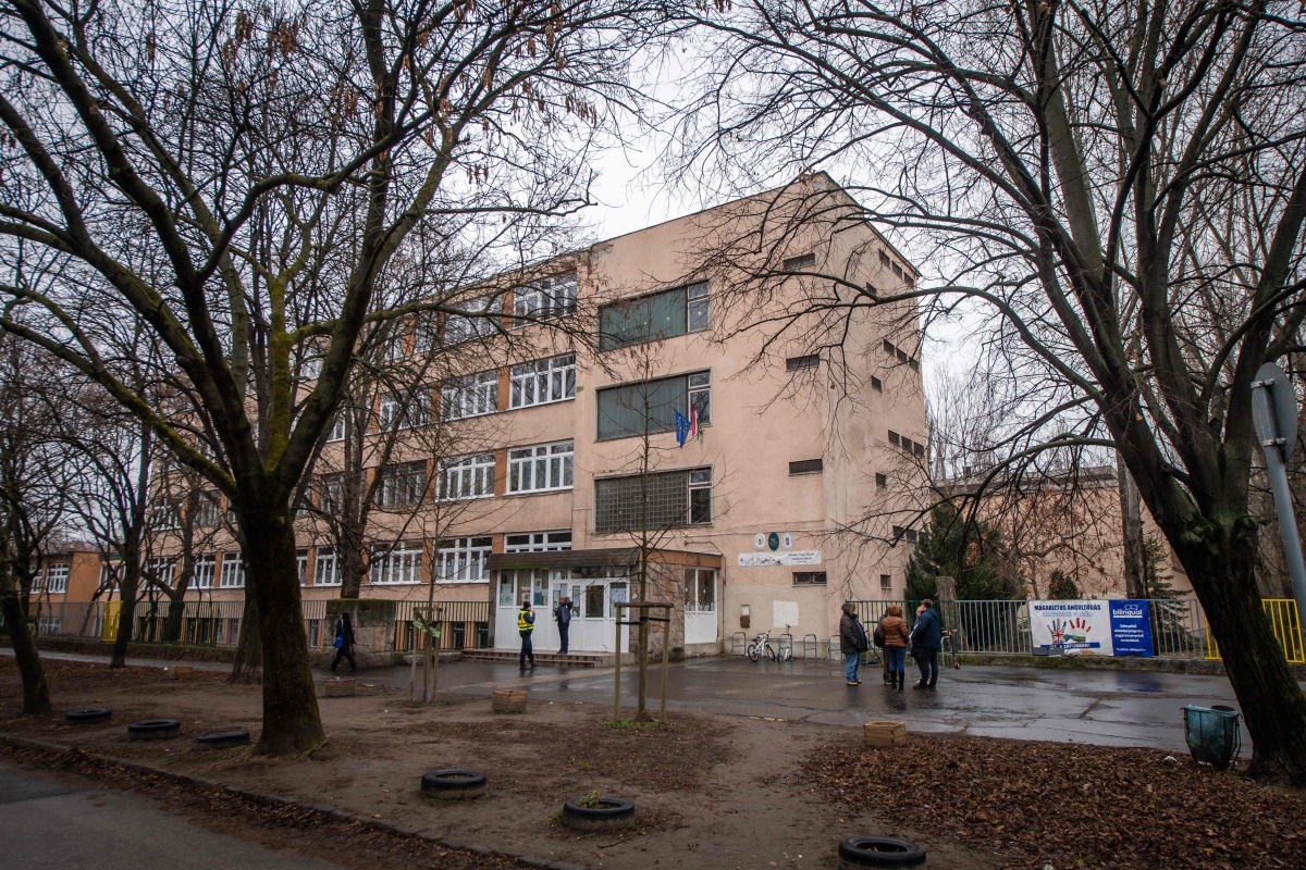 People stand in front of an empty school in Budapest on January 23, 2025 following bomb threats. (Photo by FERENC ISZA / AFP)
