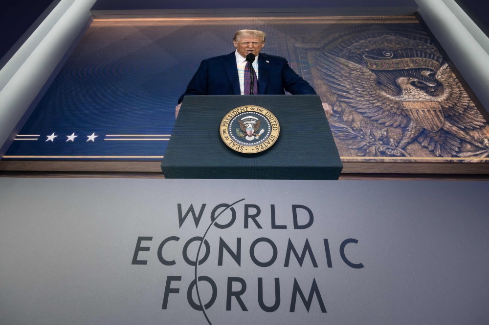 US President Donald Trump is seen on a large screen during his address by video conference at the World Economic Forum (WEF) annual meeting in Davos on January 23, 2025 (Photo by Fabrice Coffrini / AFP)
