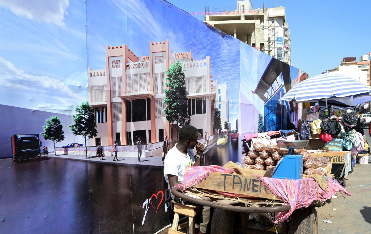A street vendor sells dates next to a construction site in Dakar on January 13, 2025. (Photo by SEYLLOU / AFP)

