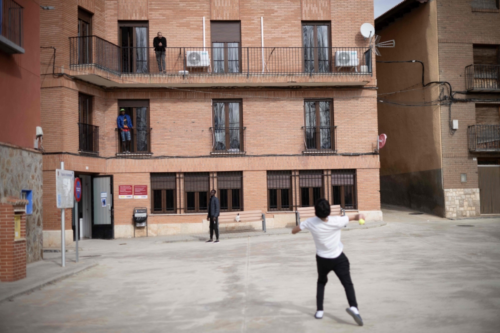 Refugees play with a ball in front of Accem association's residence, in Burbaguena, near Teruel, on February 10, 2025. (Photo by Josep LAGO / AFP)
 