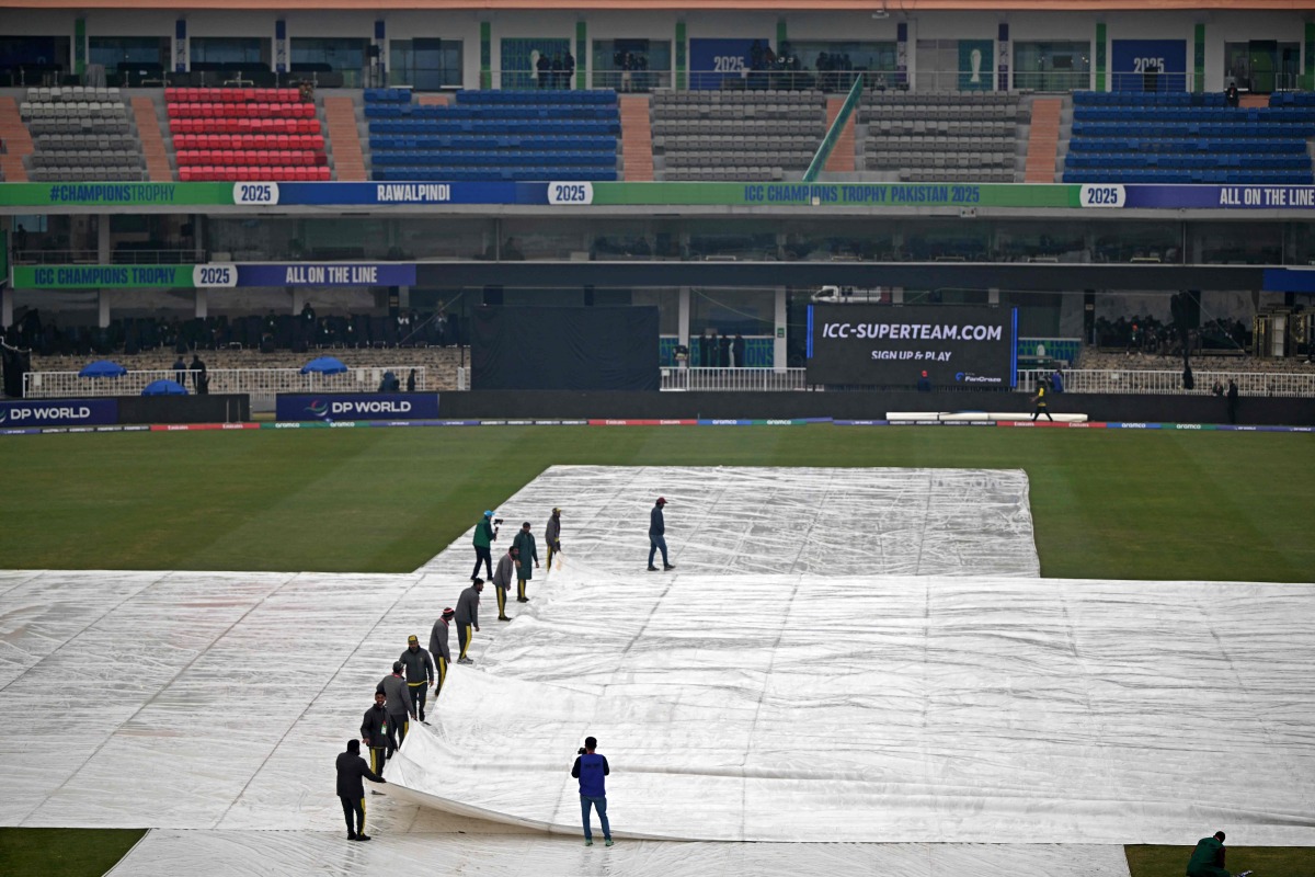 Groundmen cover the pitch as it rains before the start of the ICC Champions Trophy one-day international (ODI) cricket match between Australia and South Africa at the Rawalpindi Cricket Stadium in Rawalpindi on February 25, 2025. (Photo by Farooq NAEEM / AFP)
