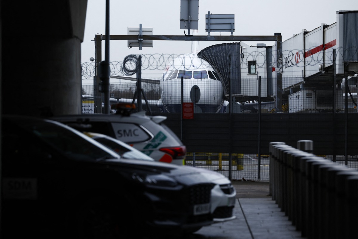 A photograph taken on March 21, 2025 shows a plane parked on the tarmac at Heathrow airport following its closure after a fire broke out at a substation supplying power of the airport, in Hayes, west London. Photo by BENJAMIN CREMEL / AFP.
