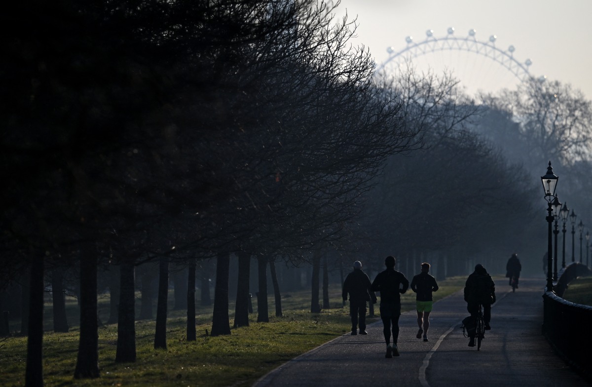 Cyclists ride past joggers running in Hyde Park in central London on March 19, 2025. (Photo by JUSTIN TALLIS / AFP)
