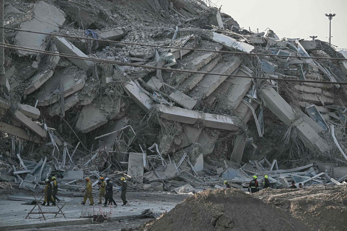 Rescue workers walk past debris of a construction site after a building collapsed in Bangkok on March 28, 2025, following an earthquake. Photo by Lillian SUWANRUMPHA / AFP