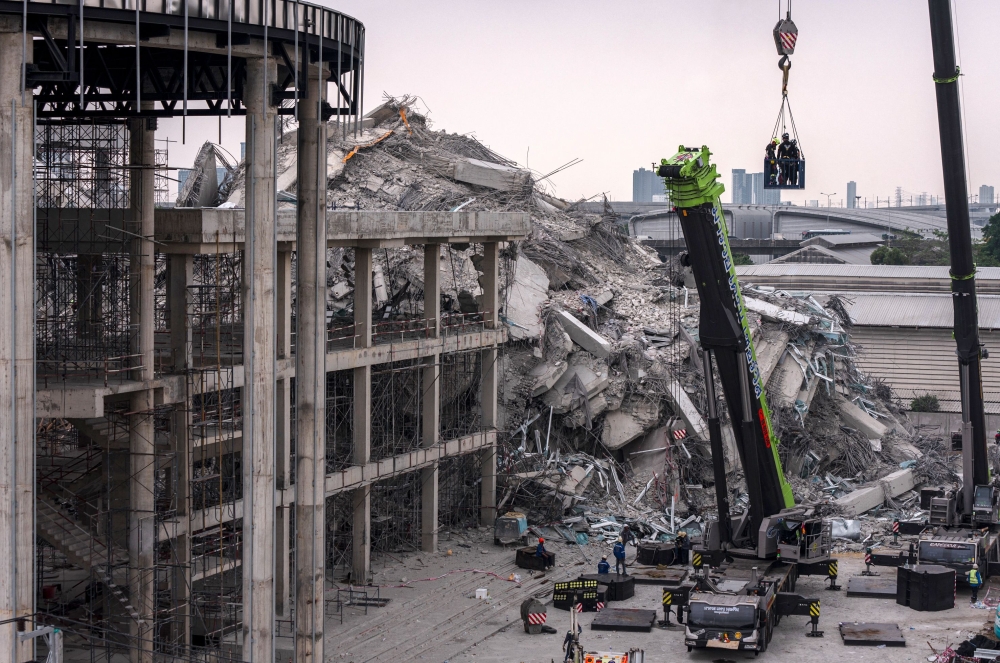 Rescue workers are lifted on a crane during search-and-rescue operations at the site of an under-construction building collapse in Bangkok on March 31, 2025. (Photo by Chanakarn Laosarakham / AFP)