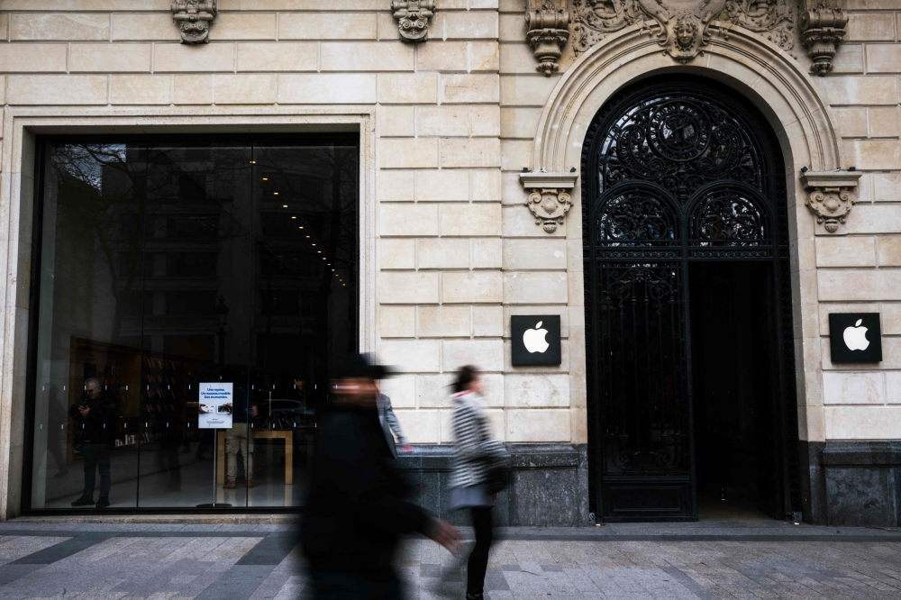 (Files) Pedestrians walk past an Apple store on the Champs-Elysees avenue in Paris, on March 18, 2024. (Photo by Julie Sebadelha / AFP)