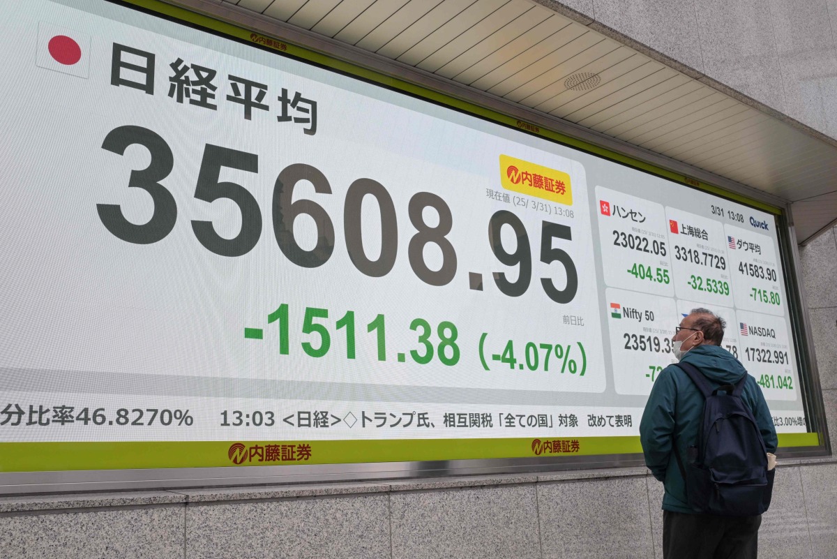 A man looks at an electronic board displaying the numbers on the Tokyo Stock Exchange, showing the market down over four percent, in early afternoon trading in Tokyo on March 31, 2025. (Photo by Richard A. Brooks / AFP)
