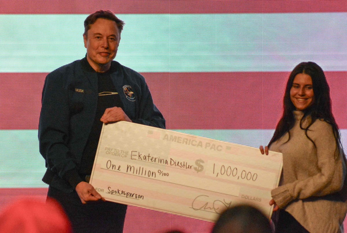 Elon Musk gives a $1 million check made to the order of Ekaterina Diesler during a town hall in Green Bay, Wisconsin on March 30, 2025. (Photo by Robin LEGRAND / AFP)
