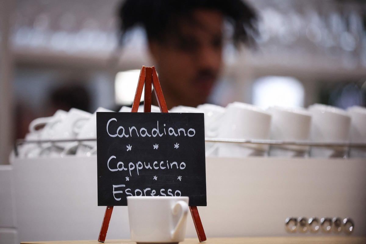 A sign reads Canadiano instead of Americano coffee at the booth of Partner country Canada at the Hannover Messe industrial trade fair for mechanical and electrical engineering and digital industries, on March 31, 2025 in Hanover, northern Germany. (Photo by RONNY HARTMANN / AFP)
