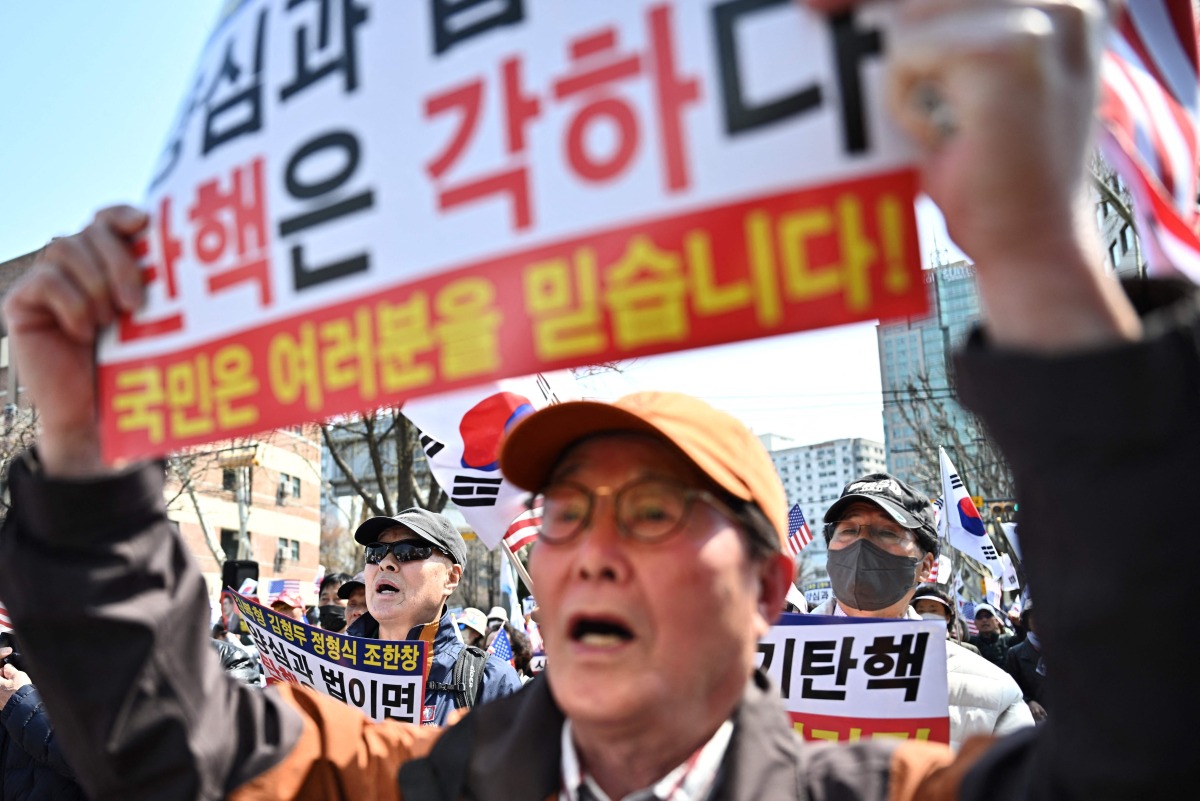 Supporters of impeached South Korean President Yoon Suk Yeol hold placards during a rally on a street in Seoul on April 3, 2025. Photo by Pedro PARDO / AFP