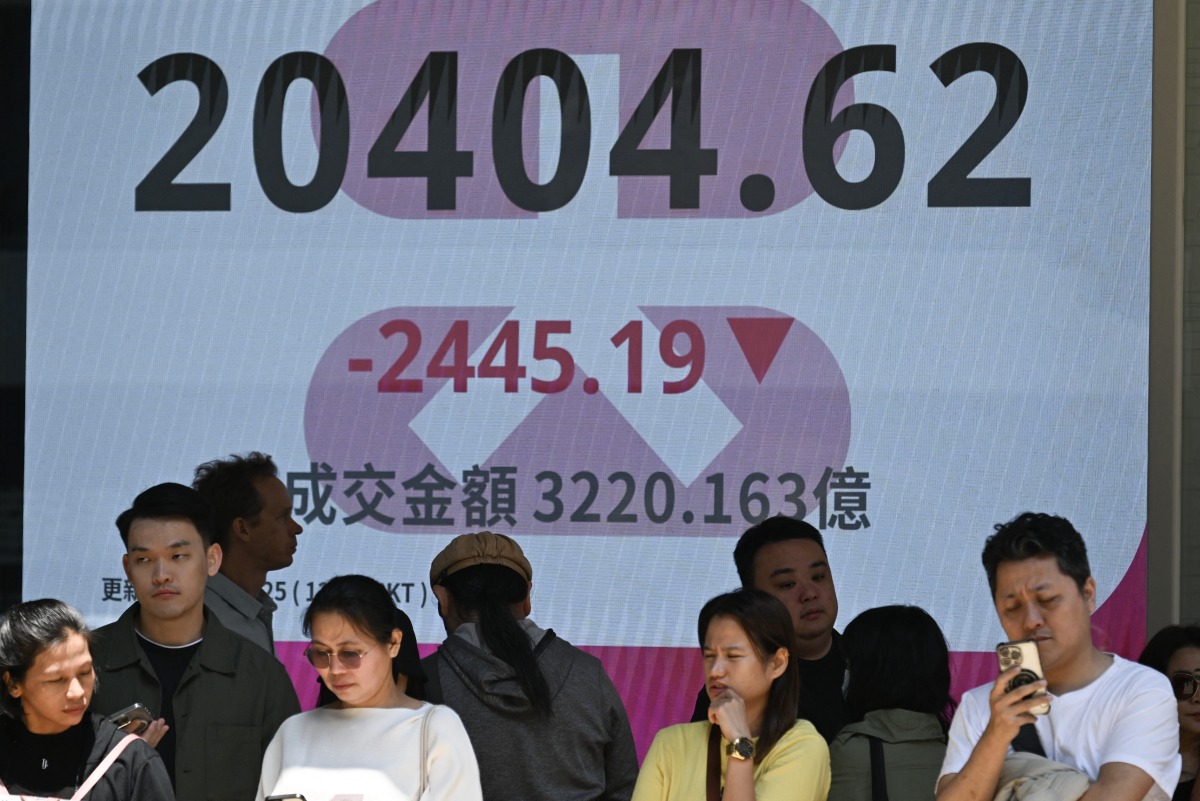 People stand in front of an electronic sign board showing the Heng Seng Index in Hong Kong on April 7, 2025. Photo by Peter PARKS / AFP