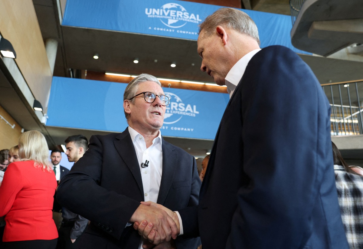 Britain's Prime Minister Keir Starmer (L) shakes hands with Comcast Corporation President Michael Cavanagh, on the day of an announcement that US media giant Comcast Corp will build its first Universal theme park and resort in Europe, set to open in 2031, during a visit to Bedford, north of London, on April 9, 2025. Photo by John Sibley / POOL / AFP