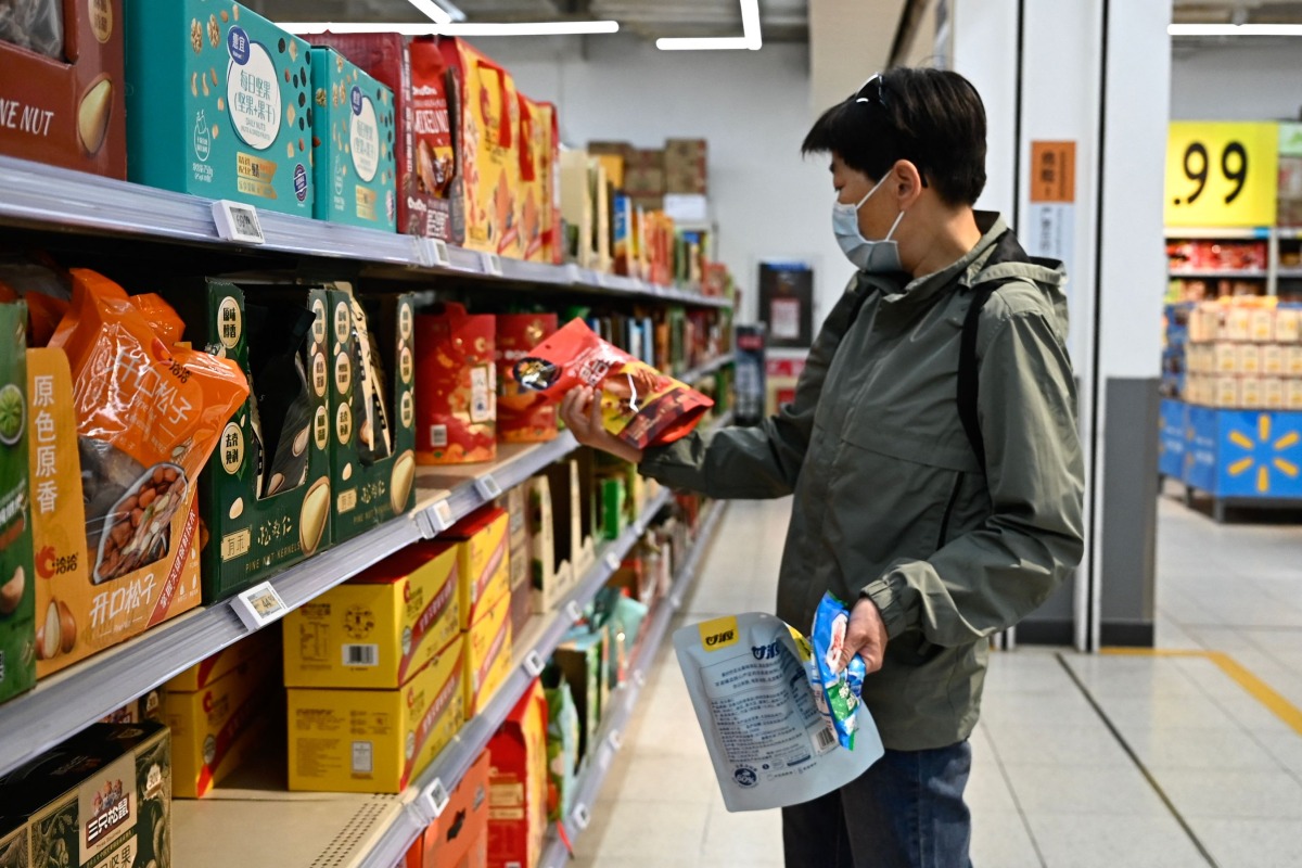 A man buys products in a supermarket in Beijing on April 10, 2025. (Photo by Pedro PARDO / AFP)
