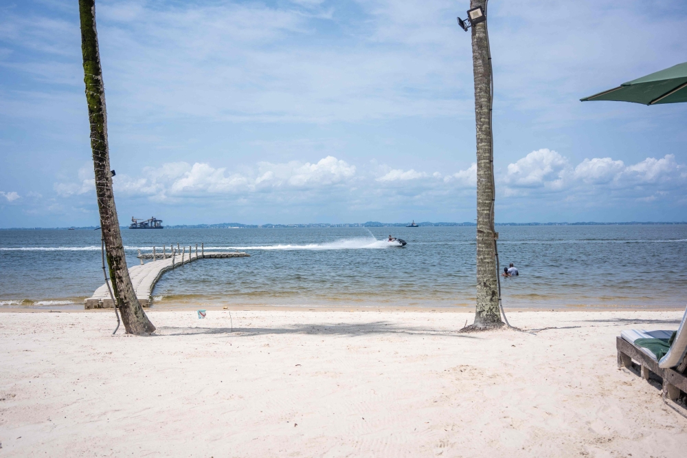 A jet-ski passes as two tourists swim at the beach at River Lodge, a hotel site located at Pointe-Denis on April 6, 2025. (Photo by Nao Mukadi / AFP)