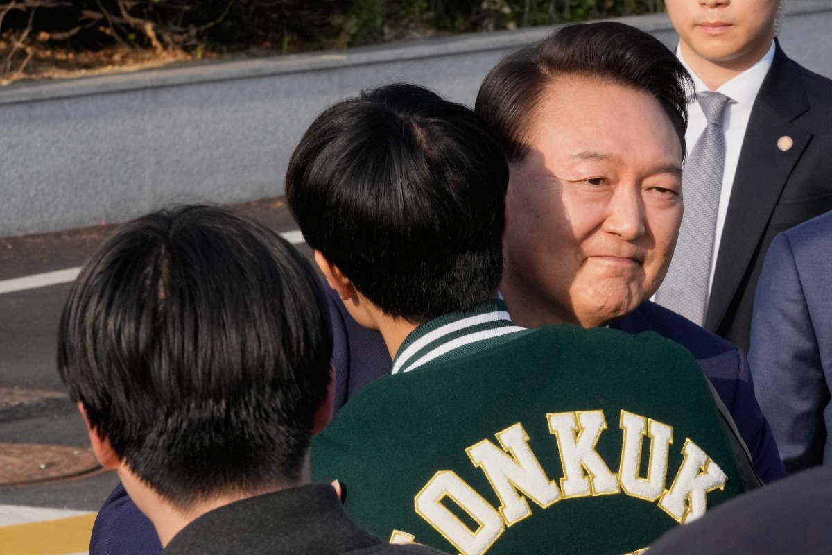 Ousted South Korean president Yoon Suk Yeol is greeted by a college student before leaving the presidential residence in Seoul on April 11, 2025. (Photo by Ahn Young-joon / POOL / AFP)