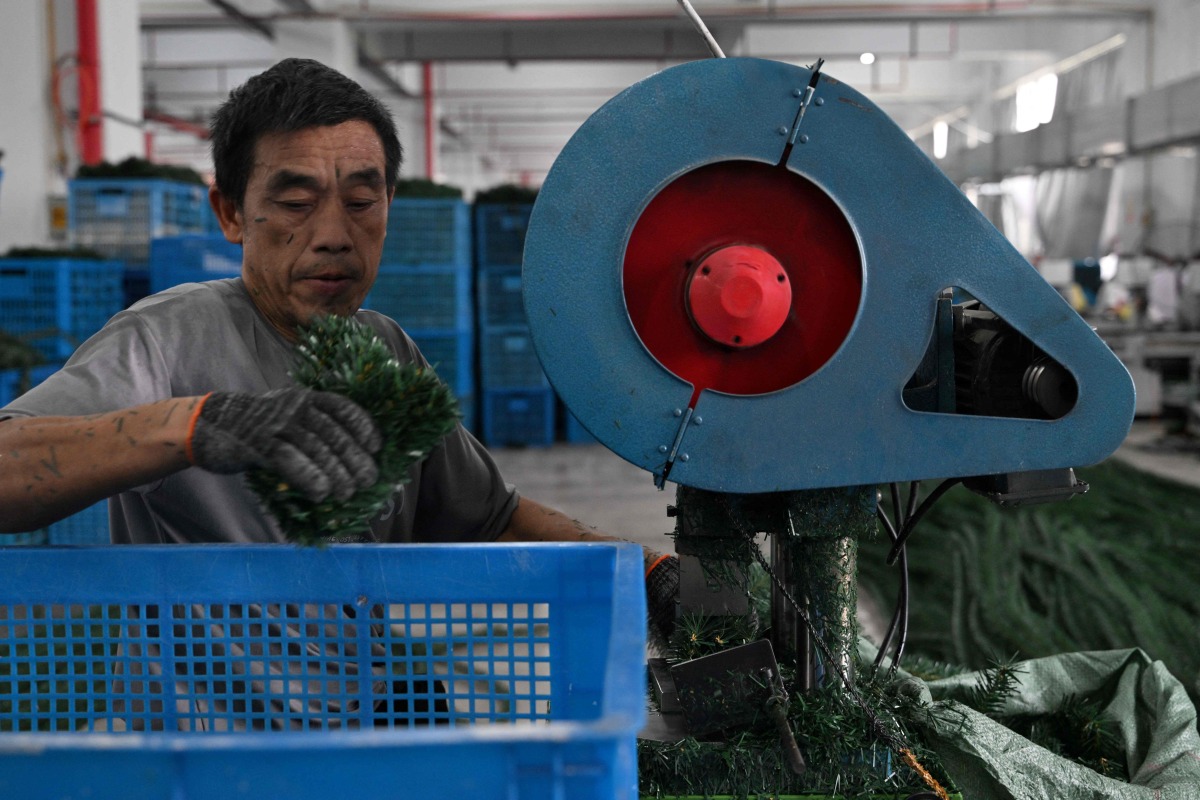 A man works at a Christmas tree factory for export and domestic markets in Jinhua, China's eastern Zhejiang province on April 11, 2025. (Photo by ADEK BERRY / AFP)
