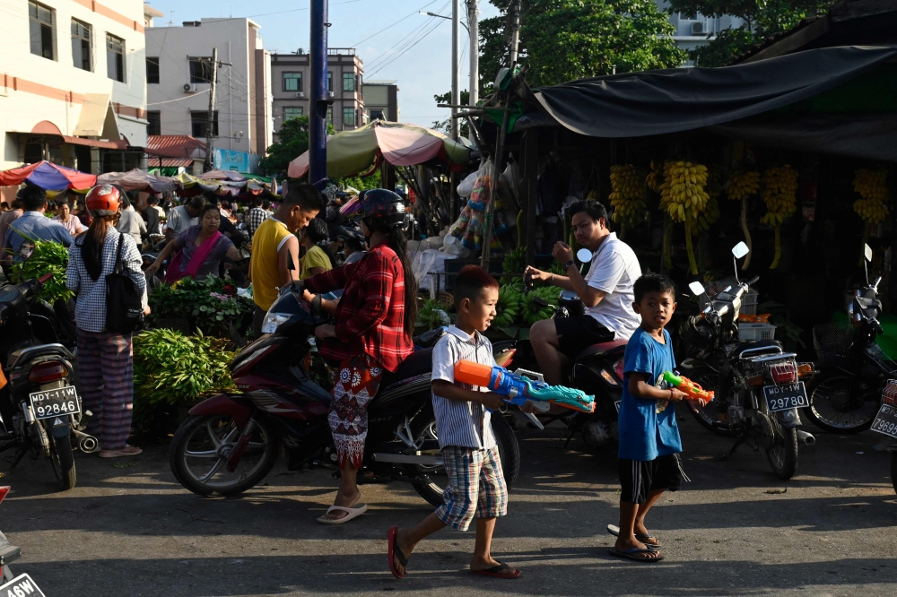Children play with water guns during Myanmar's New Year water festival, locally known as Thingyan, by a street market in Mandalay on April 13, 2025. (Photo by Sai Aung MAIN / AFP)