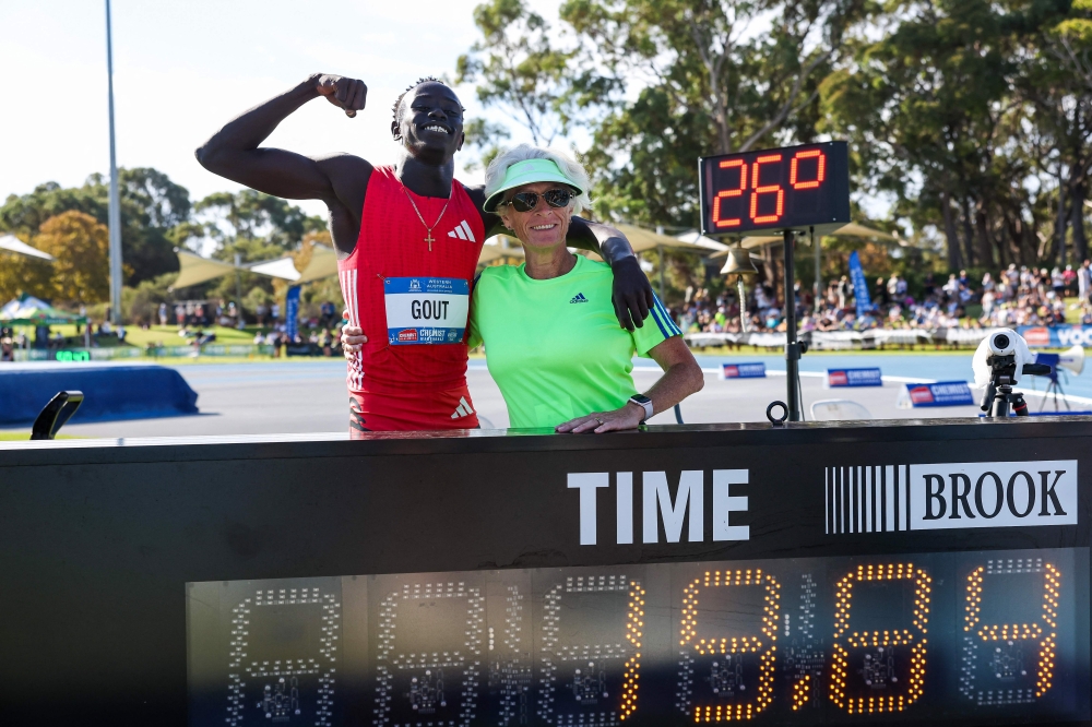 Australia's Gout Gout (L) and his coach Di Sheppard pose with his time of 19.84 as he celebrates winning the men's 200m final during the Australian Athletics Championships in Perth on April 13, 2025. (Photo by COLIN MURTY / AFP)
