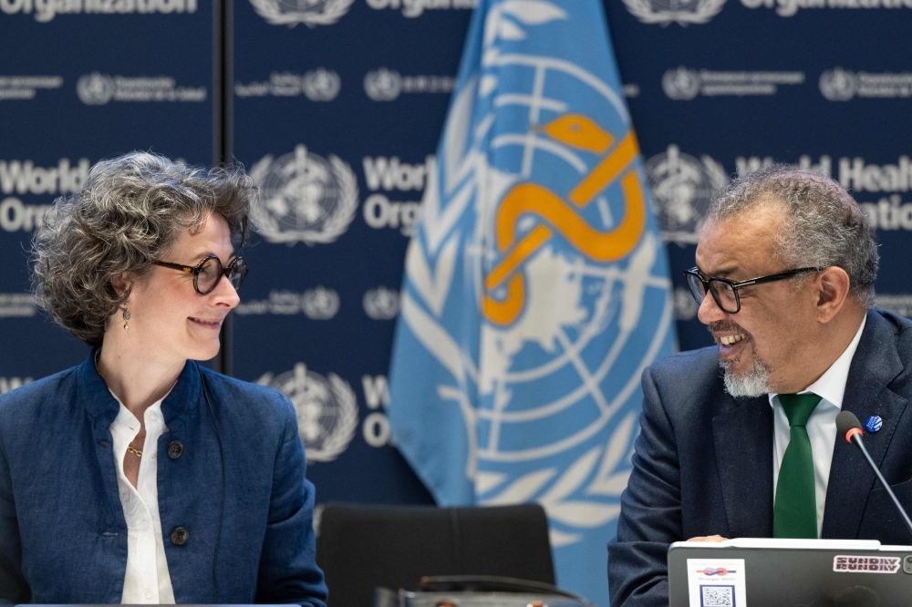 A handout photograph taken and released by the World Health Organisation (WHO) on April 16, 2025 shows Co-chair of the negotiations and French ambassador for Global Health Anne-Claire Amprou (L) and WHO Director-General Tedros Adhanom Ghebreyesus after a consensus on the Pandemic Agreement at the WHO headquarters. (Photo by Christopher Black / World Health Organization / AFP)