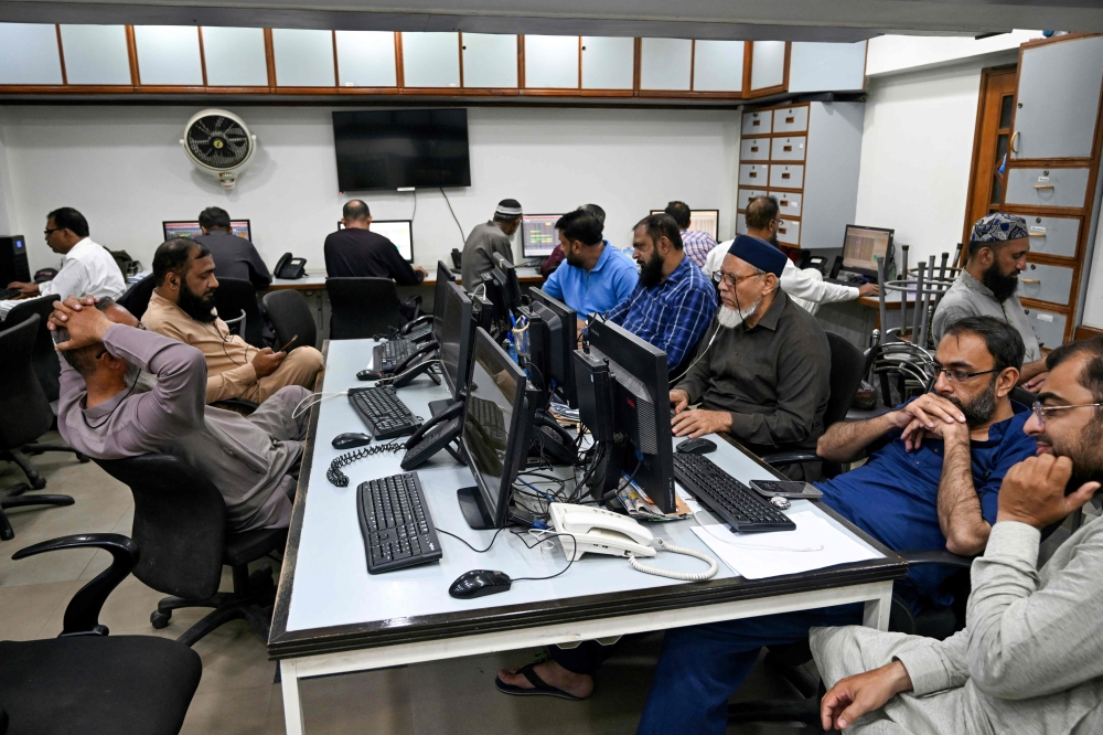 Stockbrokers monitor share prices on computers during a trading session at the Pakistan Stock Exchange (PSX) in Karachi on April 9, 2025. (Photo by Rizwan Tabassum / AFP)

