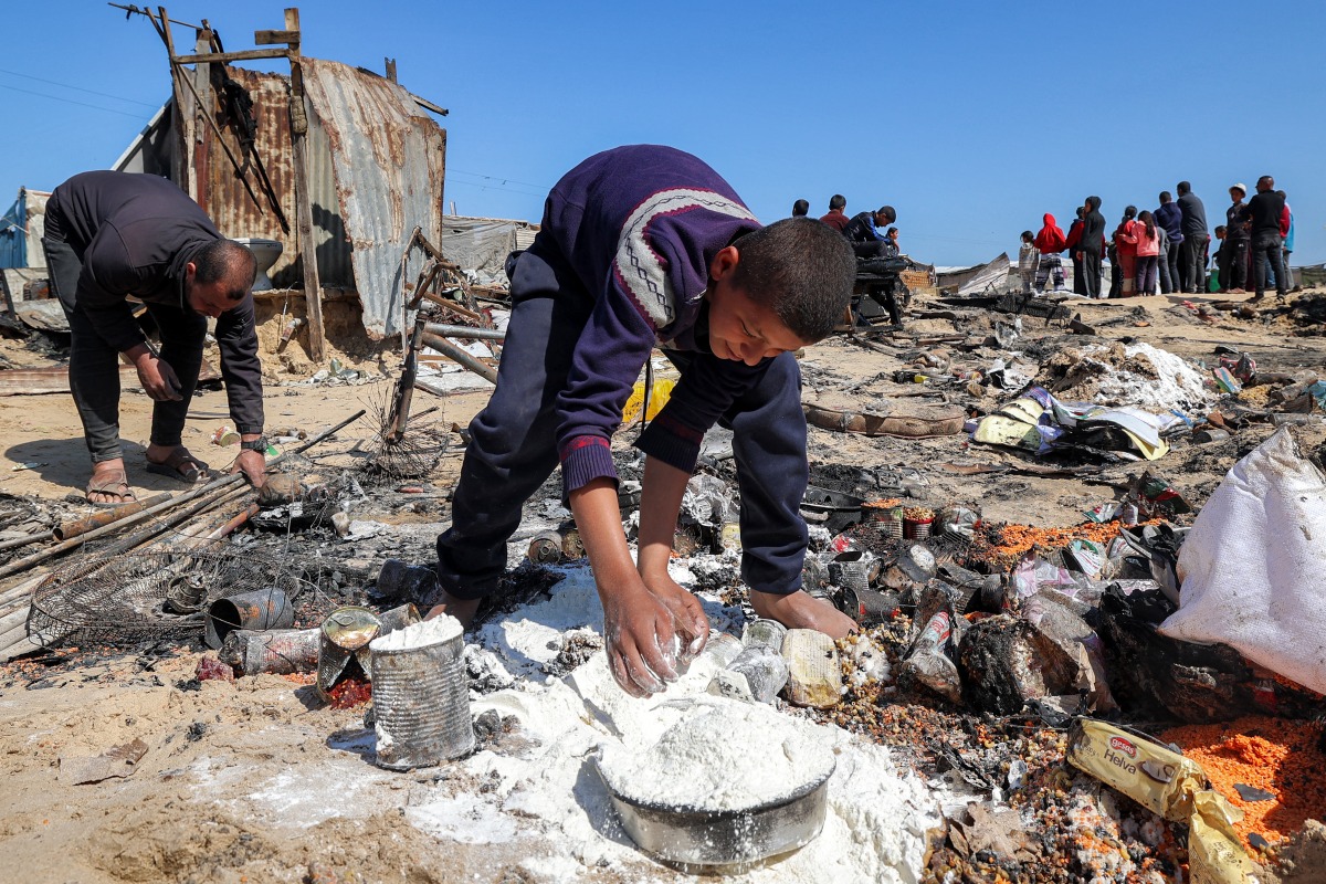 A boy salvages flour in the aftermath of a reported Israeli strike on a tent shelter in Khan Yunis in the southern Gaza Strip on April 17, 2025. Photo by Eyad BABA / AFP.