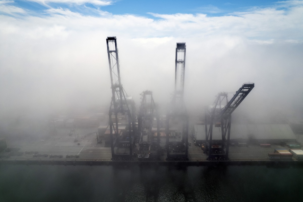 This aerial view shows container cranes amid the clouds at the Port of Ensenada in Baja California state, Mexico on April 11, 2025. (Photo by Guillermo Arias / AFP)
