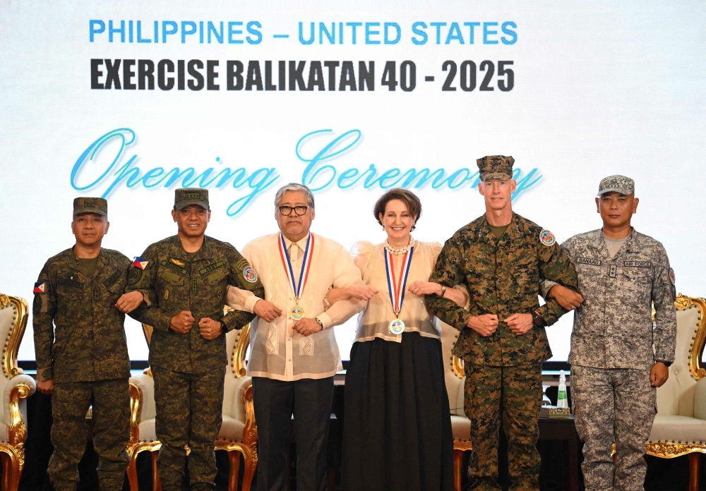 (From left) Philippines Major General Francisco Lorenzo, Philippines exercise director, Philippines military chief General Romeo Brawner, Philippines Secretary of Foreign Affairs US Ambassador to the Philippines Marykay Carlson, US marines Lieutenant General James Glynn, commander of the US marines Pacific and Philippines air force Major general Llewillyn Banaag link arms during the opening ceremony of the annual US-Philippines Balikatan joint military exercise at camp Aguinaldo in Manila on April 21, 2025. (Photo by Ted Aljibe / AFP)