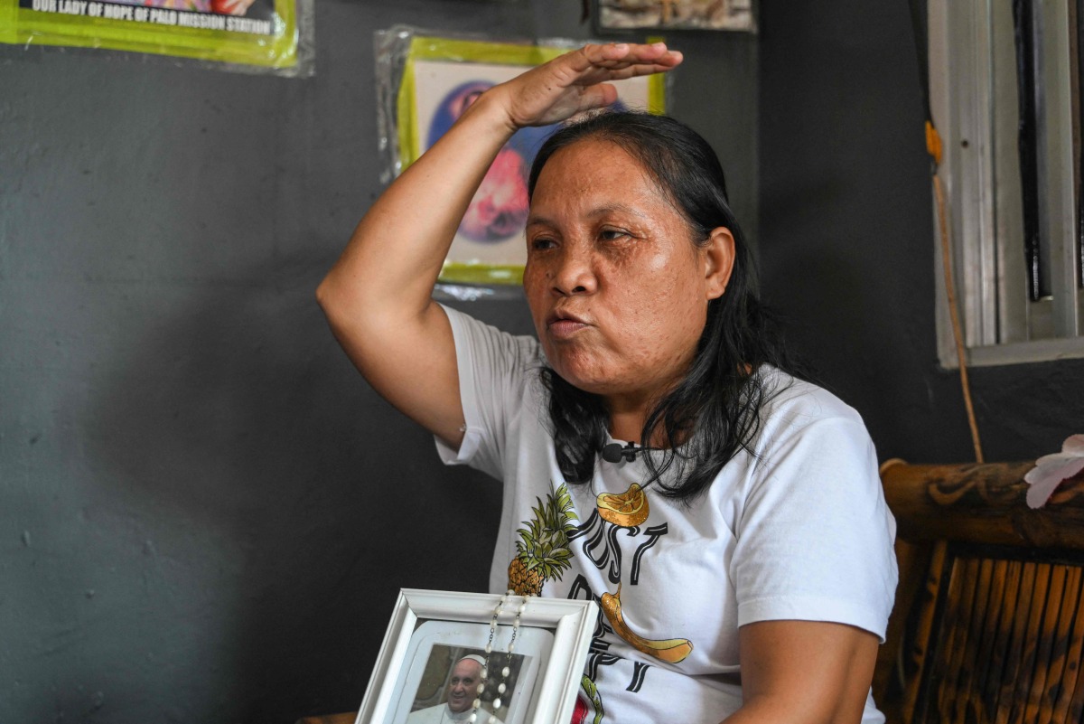 Jenita Aguilar, a member of the family that Pope Francis visited in 2015, demonstrates the Popes blessing gesture during an interview with AFP at her home in Tacloban City, province of Leyte on April 22, 2025, a day after the Pope's death. (Photo by Jam STA ROSA / AFP)