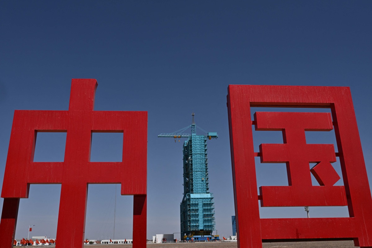 The Long March-2F carrier rocket, carrying the Shenzhou-20 spaceship, is seen encased in blue scaffolding on the launch pad a day before the launch of the Shenzhou-20 mission, at the Jiuquan Satellite Launch Centre in the Gobi desert in northwest China on April 23, 2025. Photo by Pedro Pardo / AFP