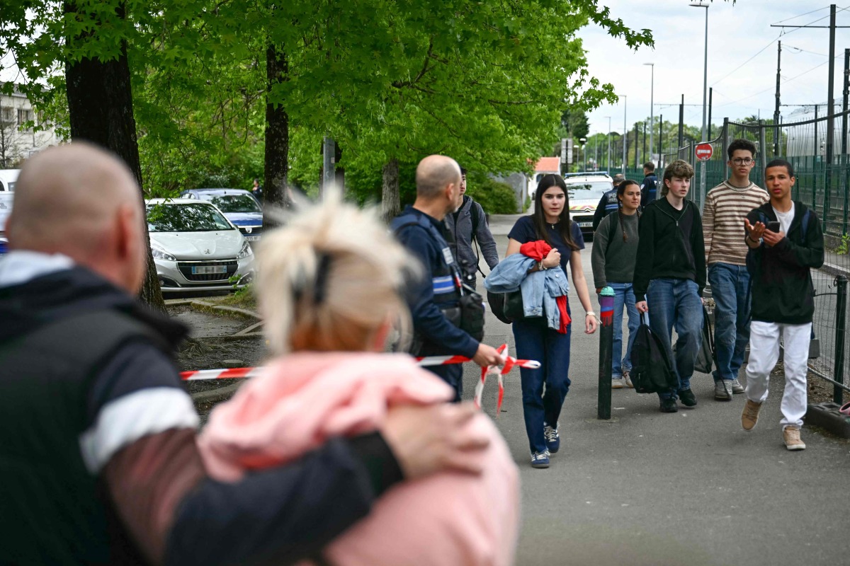 Students evacuate the high school Notre-Dame de Toutes-Aides before a Police Municipal officer surrounds the scene of crime with a Police tape after a knife attack, one student was killed and three other were wounded in Nantes, western France, on April 24, 2025. (Photo by Loic VENANCE / AFP)
