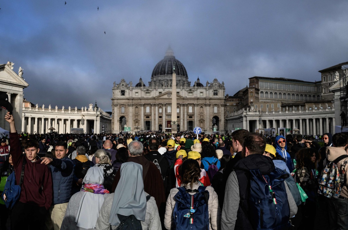 Attendees and nuns stand in front of St Peter's Basilica as they wait for late Pope Francis' funeral ceremony at St Peter's Square in The Vatican on April 26, 2025. (Photo by JEFF PACHOUD / AFP)