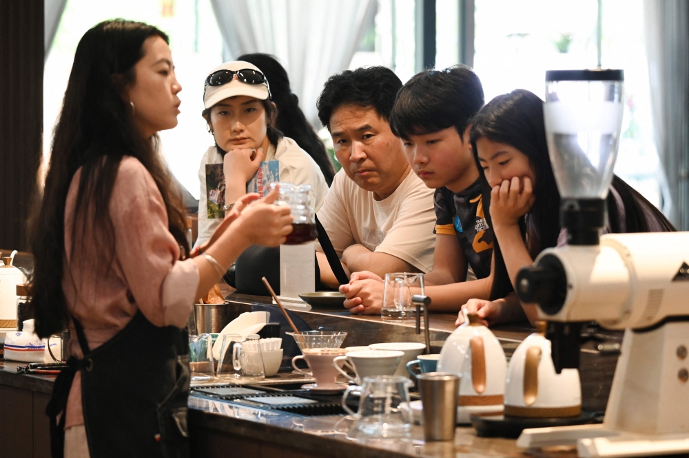 A staff member pouring coffee for guests at the Xiaowazi, or Little Hollow, coffee plantation in Pu'er. (Photo by Greg Baker / AFP) 