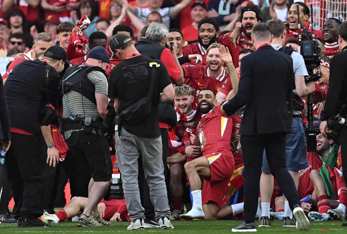 Liverpool's English midfielder #19 Harvey Elliott, Liverpool's Egyptian striker #11 Mohamed Salah, Liverpool's English defender #66 Trent Alexander-Arnold, Liverpool's English defender #02 Joe Gomez, Liverpool's Brazilian goalkeeper #01 Alisson Becker, Liverpool's Japanese midfielder #03 Wataru Endo pose with teammates after winning the English Premier League football match between Liverpool and Tottenham Hotspur at Anfield in Liverpool, north west England on April 27, 2025. Liverpool won the match 5-1, making them the winners of the Premier League title. (Photo by Paul ELLIS / AFP) 