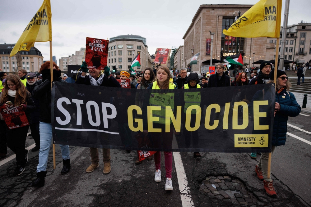 Members of Amnesty International hold a banner reading 