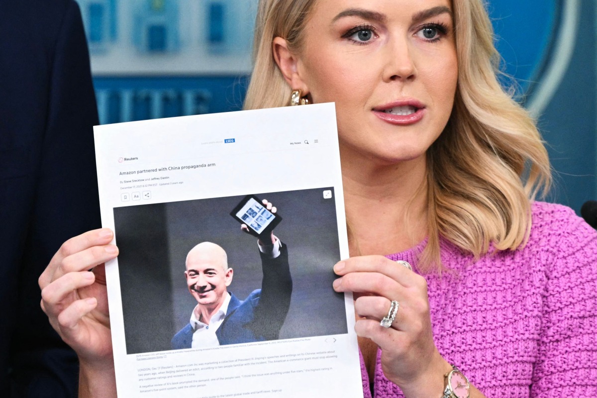 White House Press Secretary Karoline Leavitt holds a news article on Amazon CEO Jeff Bezos that reads 