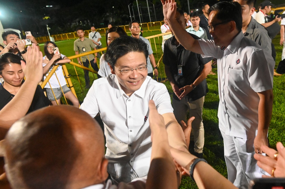 Singapore Prime Minister Lawrence Wong (2nd at R) of the People's Action Party (PAP) greets his supporters at the party's gathering centre during the general election results, in Singapore on May 3, 2025. (Photo by Roslan RAHMAN / AFP)