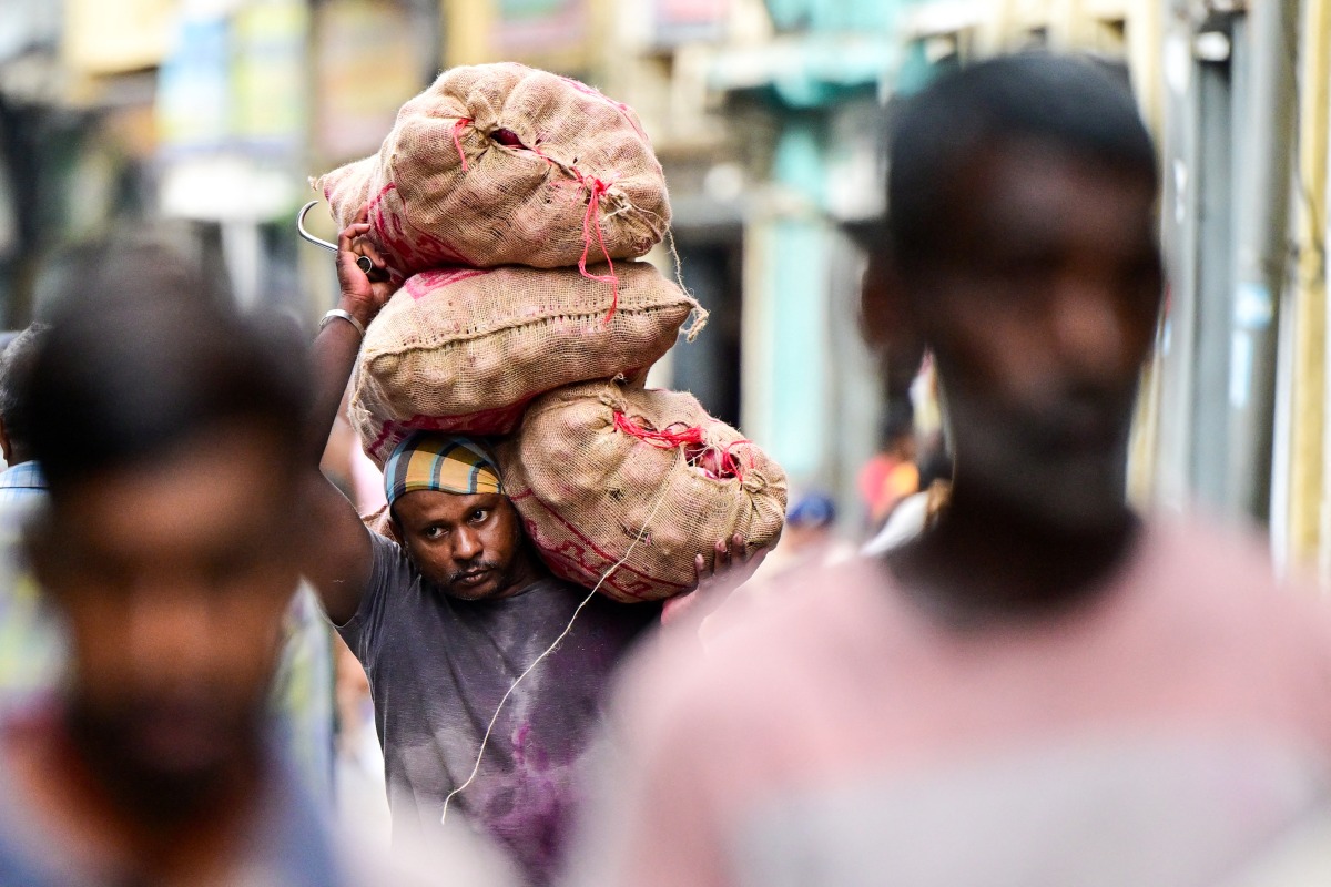 A labourer carries sacks of onions at a market in Colombo on April 30, 2025. (Photo by Ishara S. KODIKARA / AFP)
