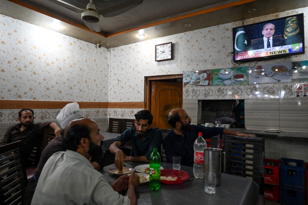 People watch a television in a restaurant as Pakistan's Prime Minister Shehbaz Sharif addresses the nation, in Islamabad on May 7, 2025. (Photo by Aamir Qureshi / AFP)