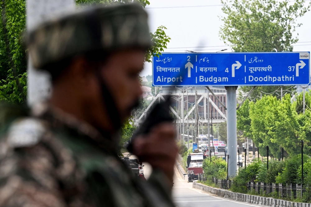 An Indian paramilitary personnel uses a handheld transceiver as he stands guard along a street leading to the international airport in Srinagar on May 10, 2025. (Photo by Sajjad Hussain / AFP)