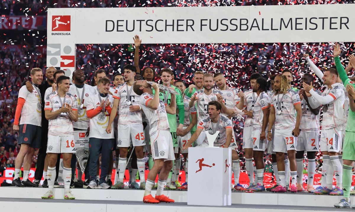 Bayern Munich players including English forward #09 Harry Kane celebrate with the trophy after the German first division Bundesliga football match between Bayern Munich and Borussia Moenchengladbach in Munich on May 10, 2025. (Photo by Alexandra BEIER / AFP)
