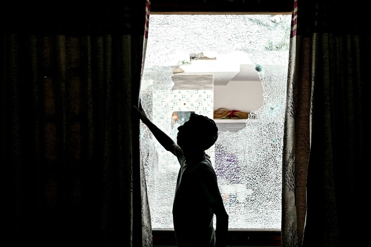 A man shows the shattered window of a house after cross-border shelling in Arnia town near the border area in India's Jammu region on May 10, 2025. (Photo by Money SHARMA / AFP)
