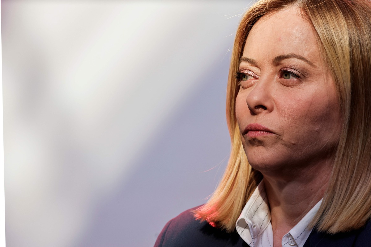 Italy's Prime Minister Giorgia Meloni looks on before posing for a family picture as part of a summit for 