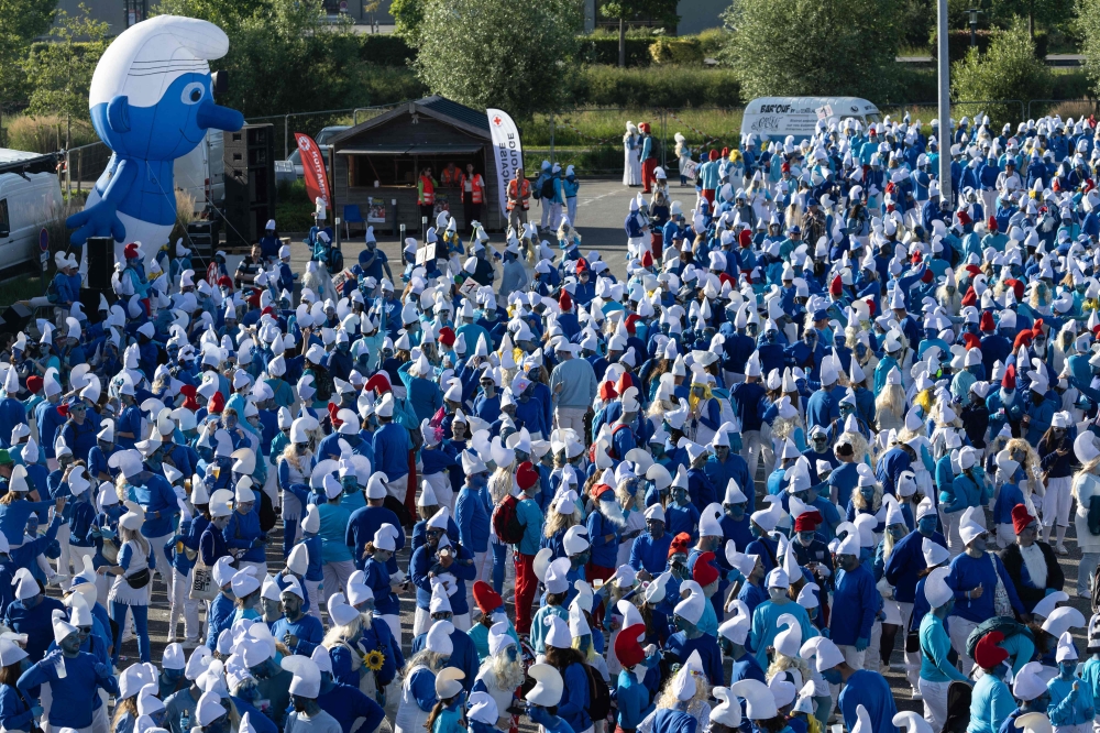 Participants wearing smurf (schtroumpf) costumes take part in an attempt to break the world record for the largest gathering of smurfs, in Landerneau, western France, on May 17, 2025. (Photo by Fred Tanneau / AFP)