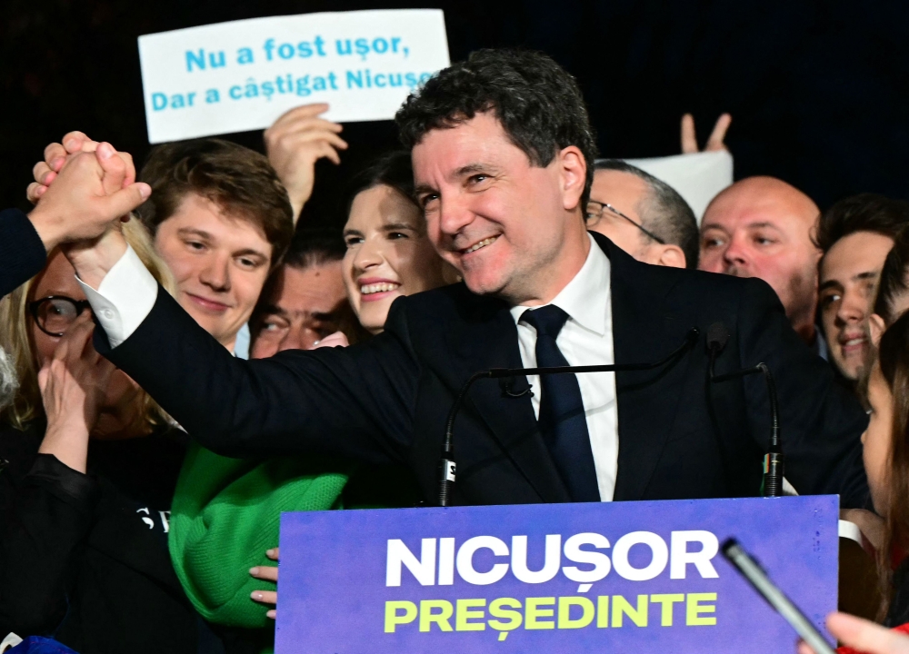 Romanian presidential candidate Nicusor Dan greets supporters after exit poll results were announced in Bucharest, on May 18, 2025. (Photo by Daniel Mihailescu / AFP)