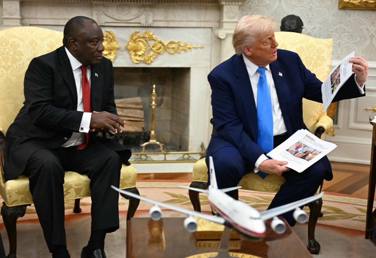 US President Donald Trump shows pictures and articles as he meets with South African President Cyril Ramaphosa in the Oval Office of the White House in Washington, DC, on May 21, 2025. 