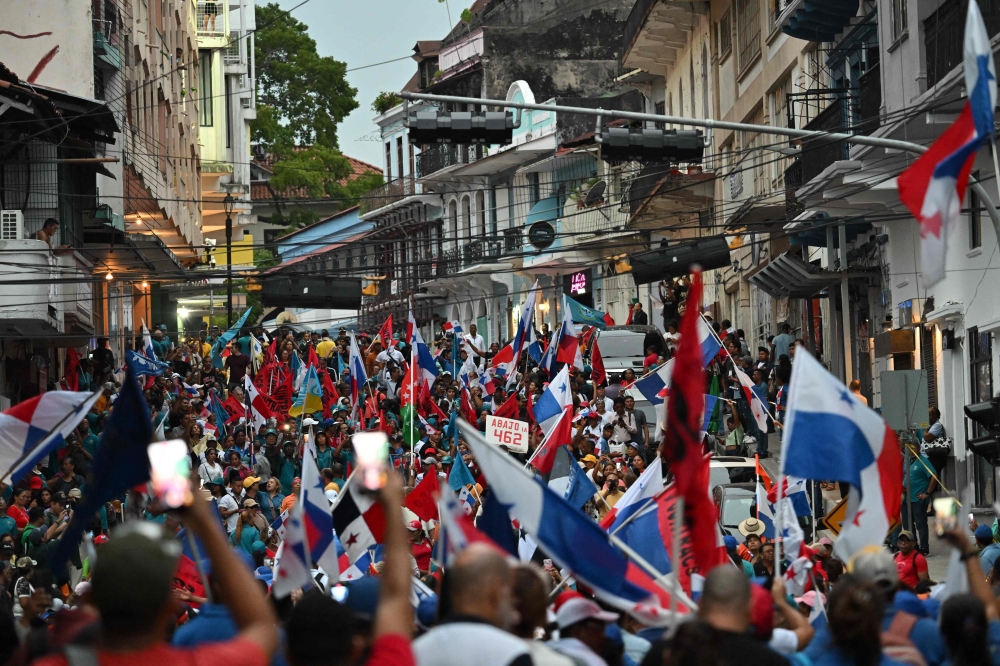 Workers carrying national flags take part in a protest against the government of President Jose Raul Mulino amid an indefinite strike in Panama City on May 23, 2025. (Photo by Martin Bernetti / AFP)