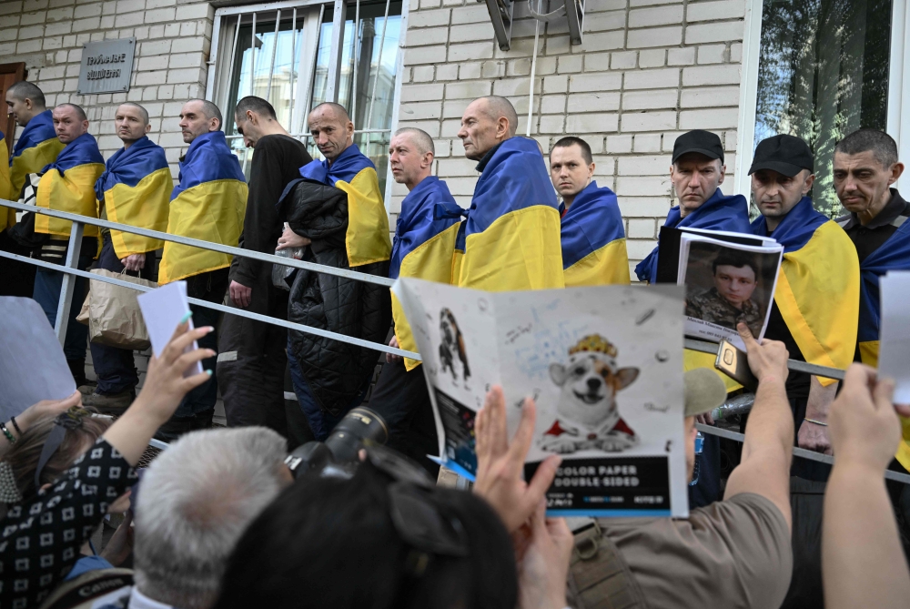 Freed Ukrainian POW upon their arrival after a prisoner exchange in the Chernygiv region look at a people which holds portraits of their missing or captured relatives and friends on May 23, 2025. (Photo by Genya Savilov / AFP)