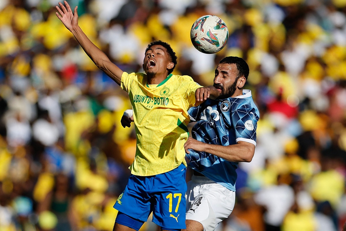 Pyramids' Egyptian midfielder #14 Mohanad Lasheen (R) jumps for the ball with Sundowns' South African forward #17 Tashreeq Matthews (L) during the first leg of the CAF Champions League final football match between Mamelodi Sundowns and Pyramids Football Club at Loftus Versfeld stadium in Pretoria on May 24, 2025. (Photo by Phill Magakoe / AFP)
