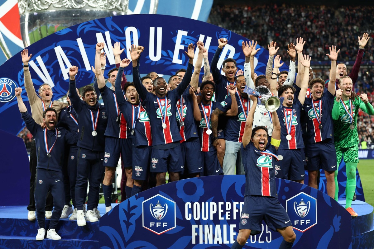 Paris Saint-Germain's Brazilian defender #05 Marquinhos (C) riases the trophy as he celebrates with teammates after winning French Cup final football match between Paris Saint-Germain (PSG) and Stade de Reims at the Stade de France in Saint-Denis, north of Paris, on May 24, 2025. (Photo by FRANCK FIFE / AFP)
