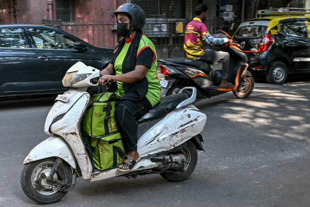 A rider leaves with customers' orders for delivery after collecting from a BigBasket dark store, in Mumbai. (Photo by Indranil Mukherjee / AFP)
